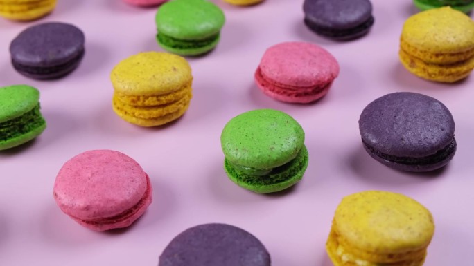 背景的甜马卡龙饼干在不同的颜色在一个粉红色的背景