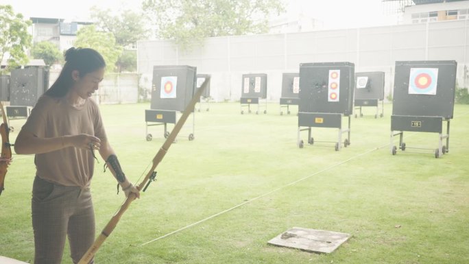 迷人的亚洲女性在靶场练习射箭。射箭。