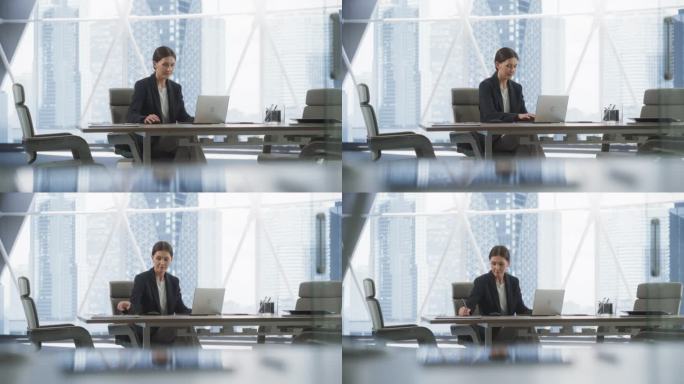 职业女性CEO在明亮的大都市转角办公室用笔记本电脑打字。白人女性独自在投资管理公司的会议室工作，寻找
