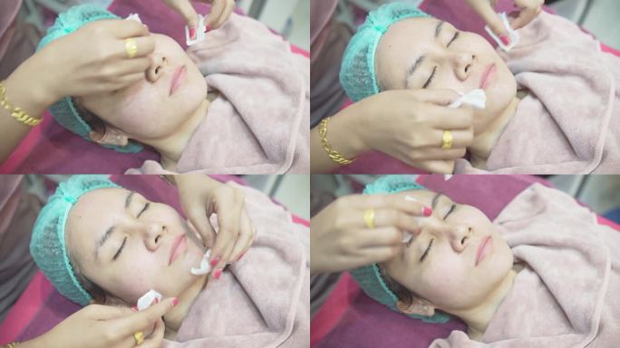 一名护士正在擦拭一名亚洲妇女的脸。在美容诊所，医疗和美容皮肤科预约概念。