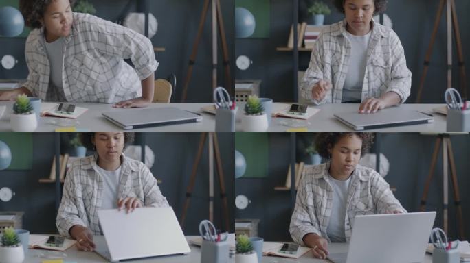 非裔美国女雇员坐在办公桌前使用笔记本电脑的慢动作肖像
