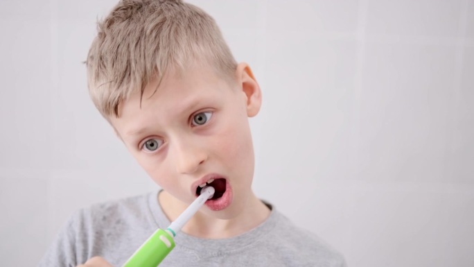 金发白种男孩用电刷刷牙。有趣的生活方式。孩子的微笑。卫生保健牙科玩牙医游戏