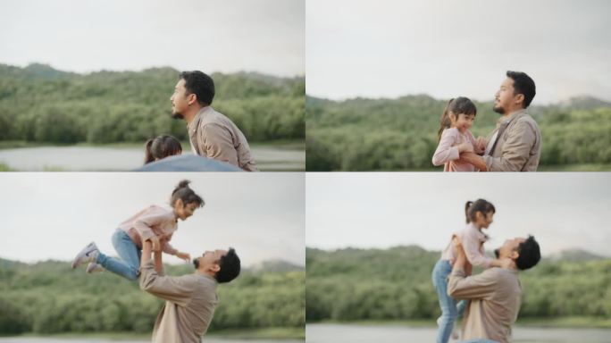 度假时，一位亚洲父亲抱着他的小女儿在草地上露营。