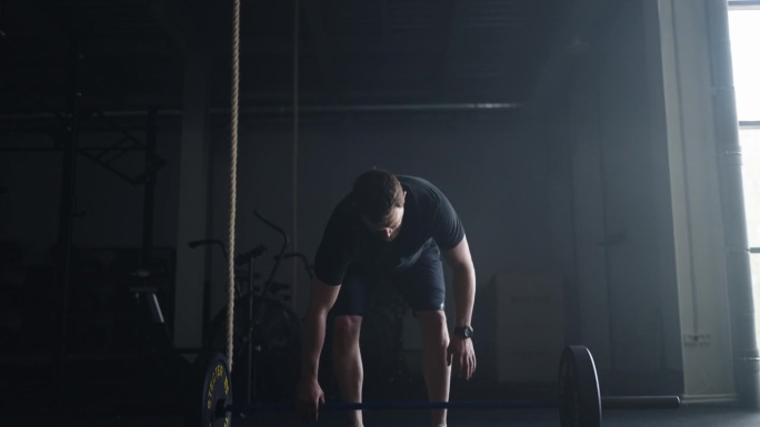积极的举重运动员在健身房的肖像，用重物投掷杠铃