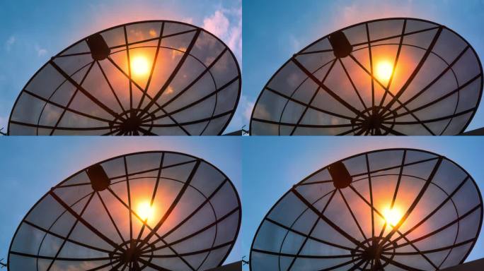 延时剪影大框架卫星碟与蓝色的天空和移动的太阳升起的看法蓝色背景。