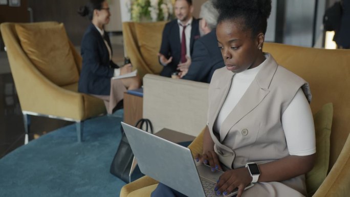 成功的非裔美国女商人在酒店大堂用笔记本电脑工作
