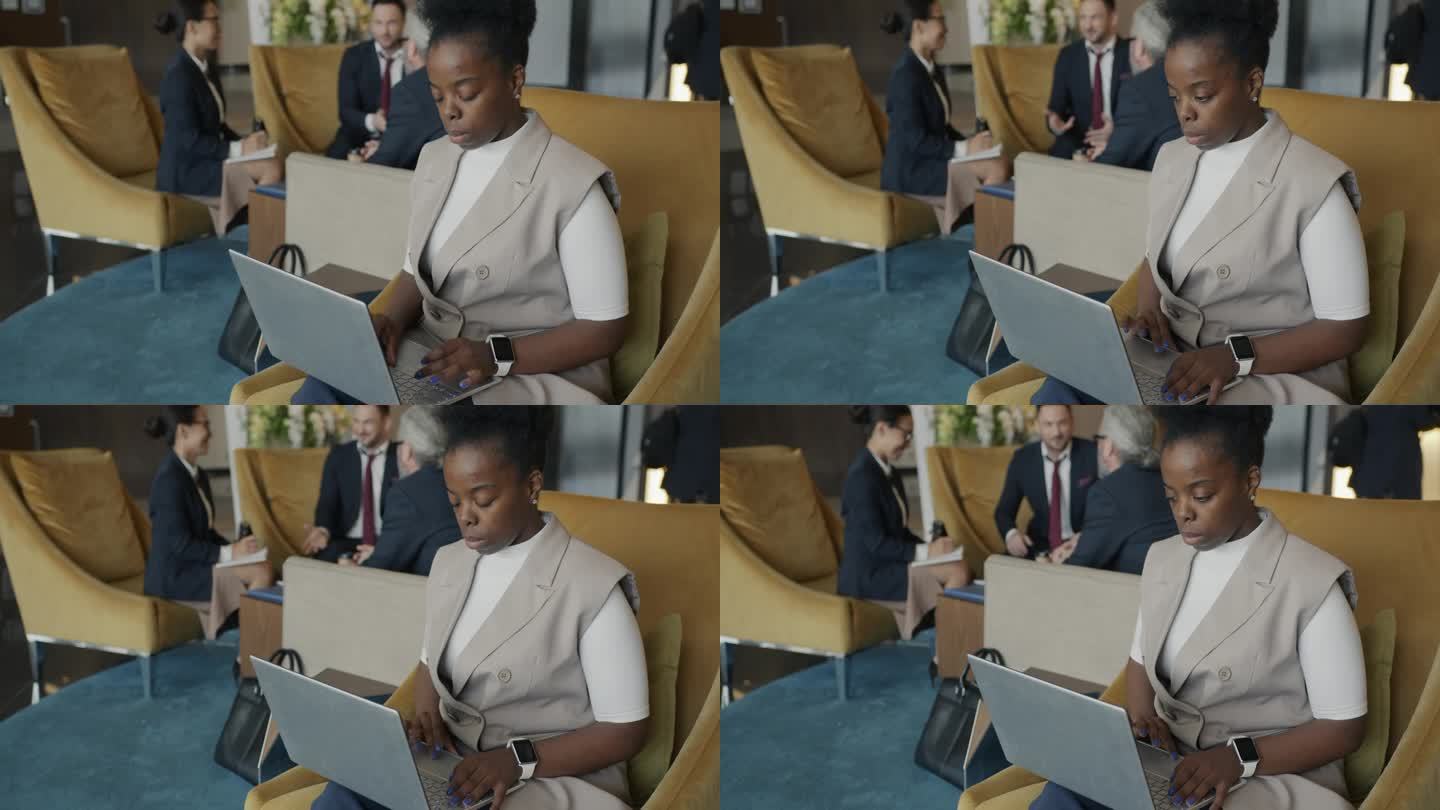 成功的非裔美国女商人在酒店大堂用笔记本电脑工作
