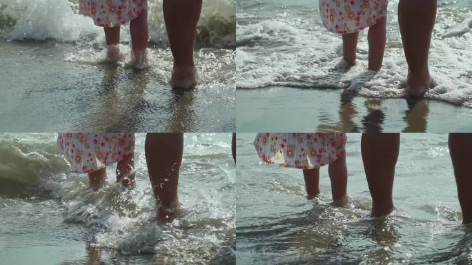 妈妈和宝宝光着脚站在浅水区等着海浪，在海里戏水。旅游和假期的概念。慢动作