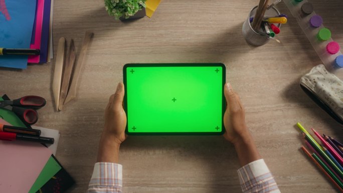 有创意的多种族黑人艺术家拿着绿屏模拟显示器的平板电脑，上面放着艺术用品。视频模板的数字演示，设计内容