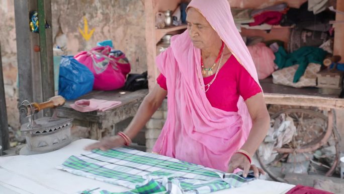 一位年长的印度妇女正在熨衣服