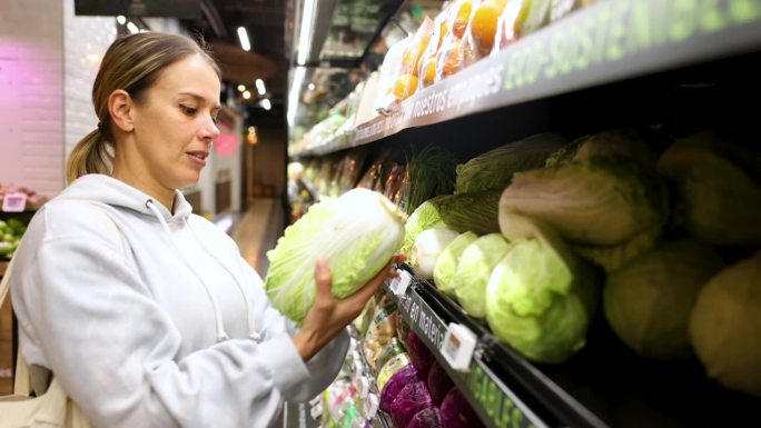 一位拉丁美洲的健康妇女在超市的冷藏农产品区购买蔬菜