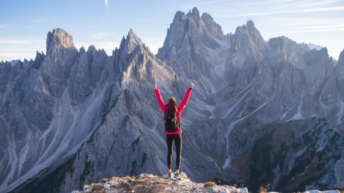 高举双手的女性徒步旅行者站在雄伟的山谷之上