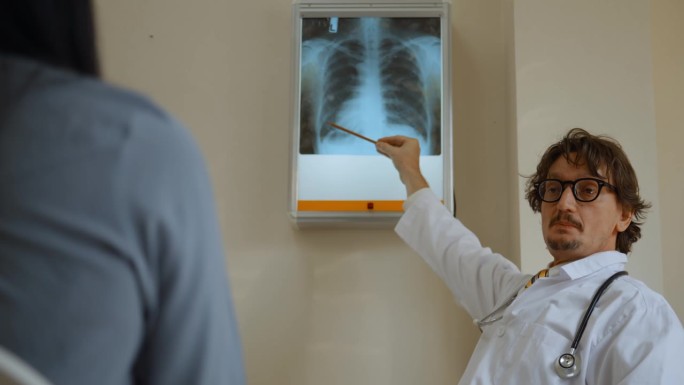 一位医学专家正在向病人解释x光片上的伤情。