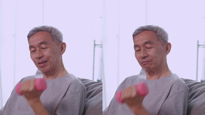 垂直夹。亚洲老人在家里用哑铃做运动。这位老人每天锻炼身体以保持健康。