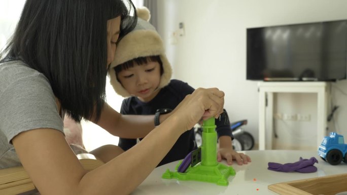 小男孩戴着帽子跟妈妈玩橡皮泥面团和建筑布景，慢动作场景