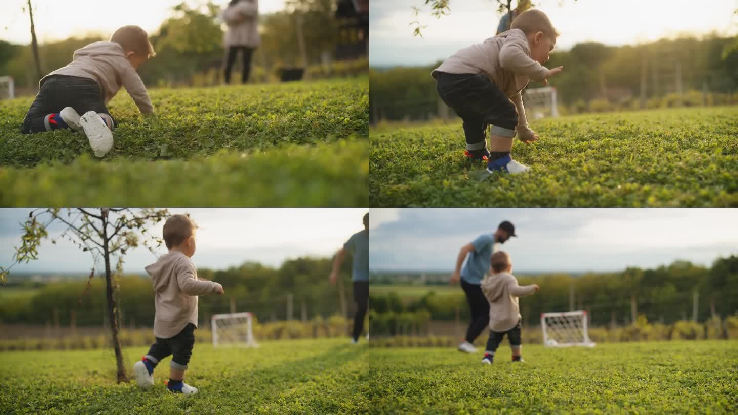小男孩学着走路，和爸爸在操场上踢足球。幸福的爸爸