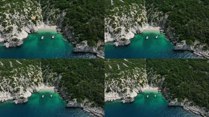 航拍无人机的帆船停泊在清澈的水岩石海岸线