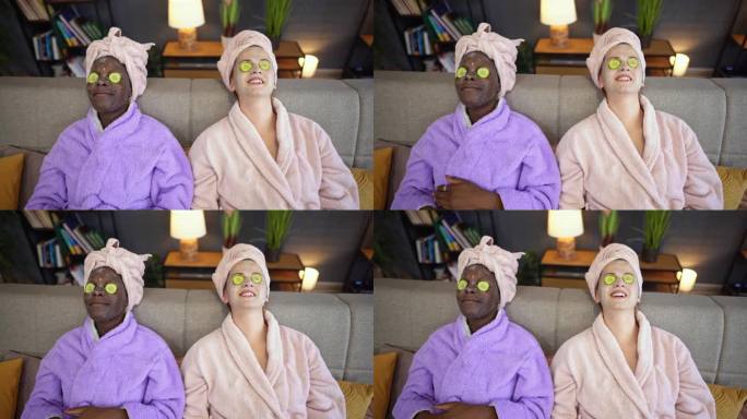 两个多种族的女性朋友带着口罩和黄瓜眼圈躺在床上放松