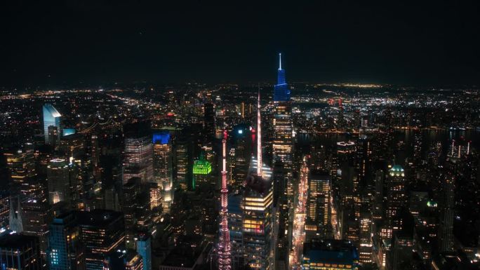 纽约市的夜间航拍镜头，摩天大楼的尖顶和笔直繁忙的街道上有汽车和黄色出租车。从直升机上俯瞰大城市中心的