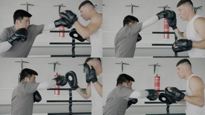 亚洲运动员慢动作训练与教练高加索男子拳击集中拳在健身房