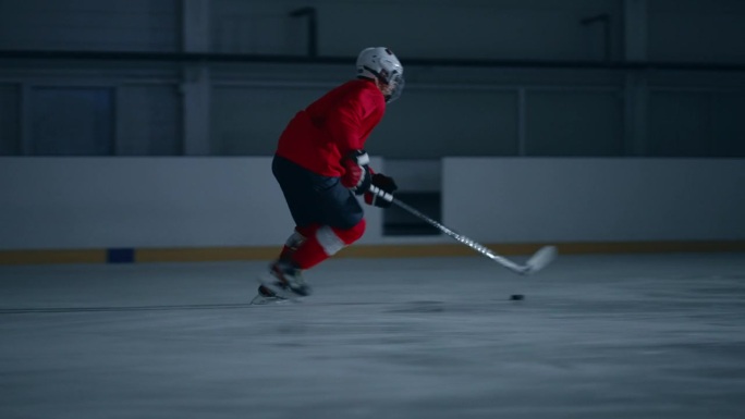 专业的冰球运动员在溜冰场上用冰球棍射击、击球和击打冰球。运动员进球与戏剧性的广角镜头和电影般的灯光。
