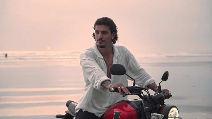 骑摩托车或在美丽的大自然的海滩户外旅行。有吸引力的赛车手男子摩托车与动力摩托车骑沙子在快速行动。成人