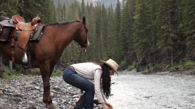 女骑手牵着马沿着河岸走