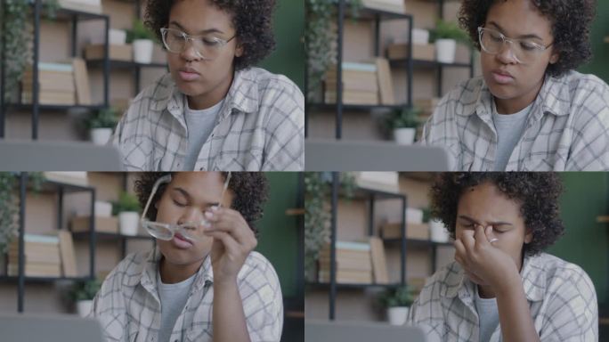 疲惫的雇员非裔美国妇女用笔记本电脑揉揉脸和眼睛感到疲惫