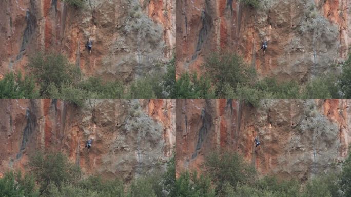 登山者在高山自然的高岩壁上攀岩的鸟瞰图