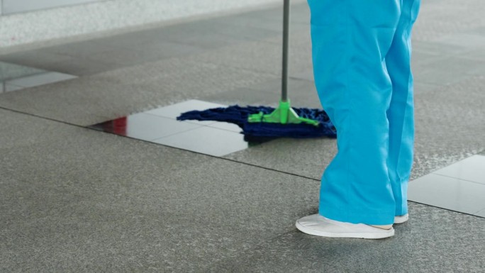 贴身的腿丫鬟在打扫一个地方，被人用拖把弄脏的地板，正在擦光亮的玻璃区域，以便给美丽的光泽，穿着蓝色的