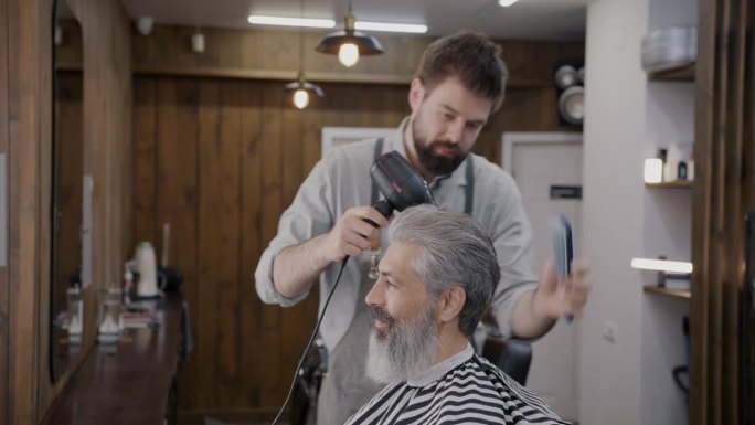 专业理发师在现代理发店为顾客梳头和使用吹风机