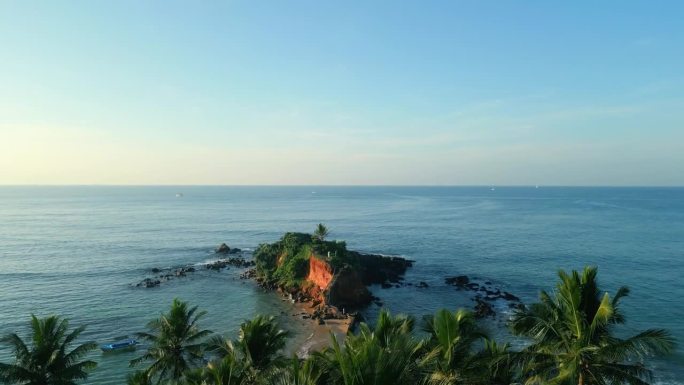 绿色的热带岩石岛，位于被海浪冲刷的蓝绿色海洋中间，鸟瞰棕榈树。在斯里兰卡的米里萨，鹦鹉岩被无人机拍摄