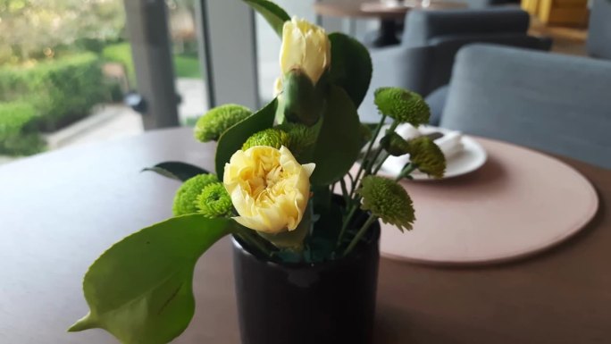 餐馆里小壶里的黄玫瑰