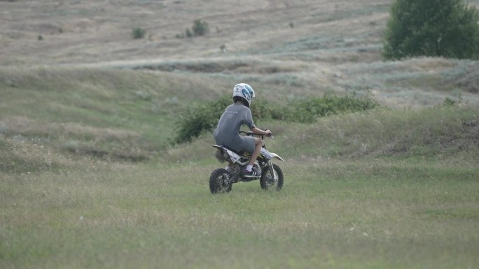 摩托车赛车手男孩的后视图准备摩托车越野赛。