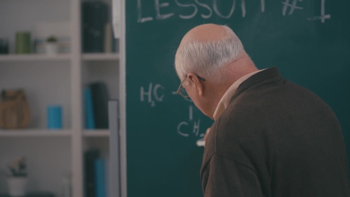 男老老师在黑板上写化学方程式，讲解任务