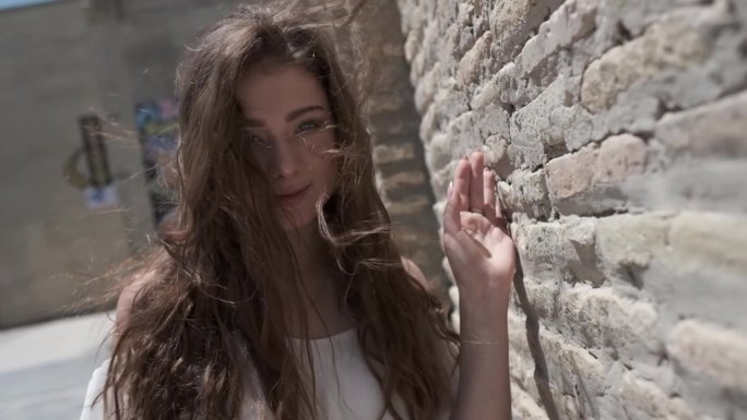 一位年轻女子，一头飘逸的长发，身穿白色背心裙，走在一座东方城市的古城墙边