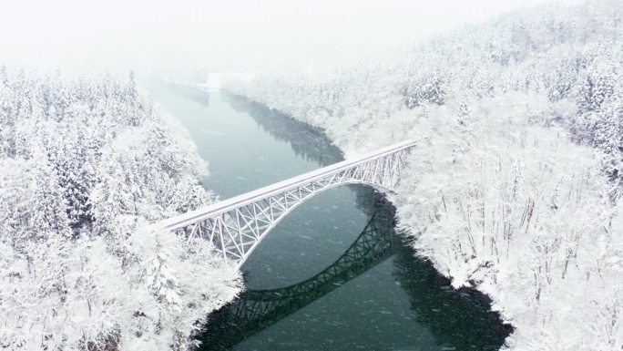 4K鸟瞰图，雪天横跨河流的山间铁路桥。