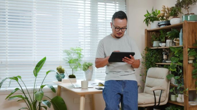 亚洲中年男性在家里摆弄数字平板电脑