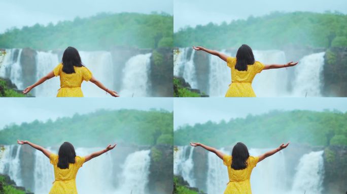 旅游少女在印度古吉拉特邦美丽的吉拉瀑布前张开双臂。在旅游目的地享受假期的女性。雨季时瀑布流动。