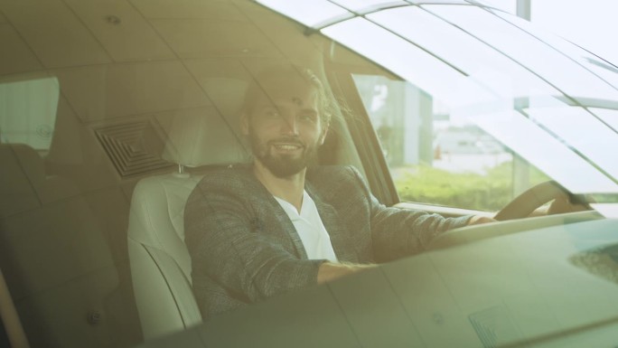 一名乐观的白人男子坐在豪车的驾驶座上，对着镜头微笑，双手握着方向盘。购买前检查车辆。男子在沙龙检查车