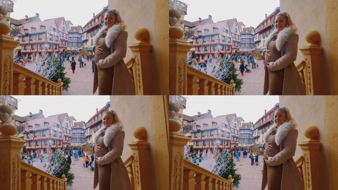 圣诞节期间，一名孕妇在科尔马镇广场的一家酒店门口摆姿势