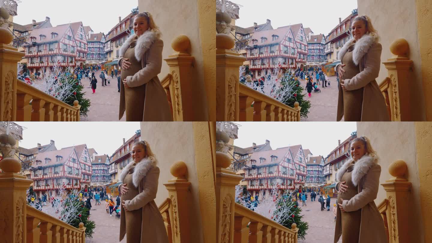 圣诞节期间，一名孕妇在科尔马镇广场的一家酒店门口摆姿势