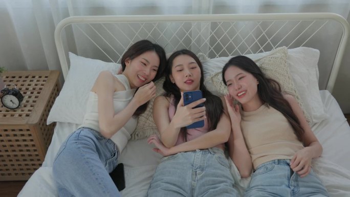 年轻亚洲女性的谈话。躺在床上看智能手机