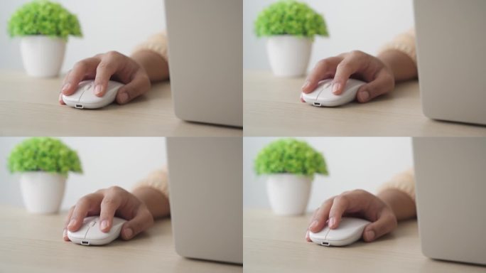 年轻女子用手点击和使用鼠标在笔记本电脑上工作