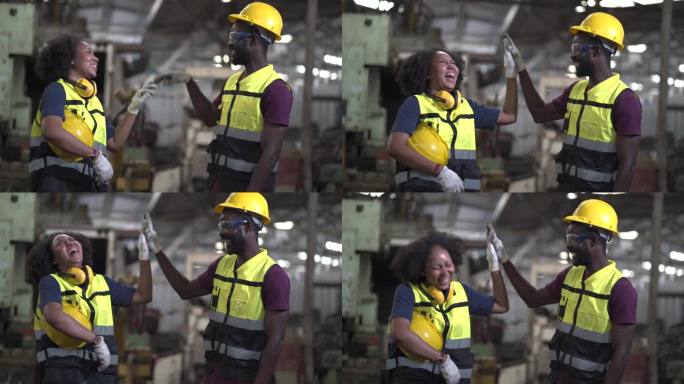 一群非裔美国工人，工程师，男人和女人兴奋和庆祝工作完成的成功一起在制造工厂击掌。黑人劳工在工作场所的