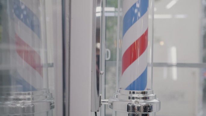理发师的杆子在理发店的玻璃墙背景下旋转的特写