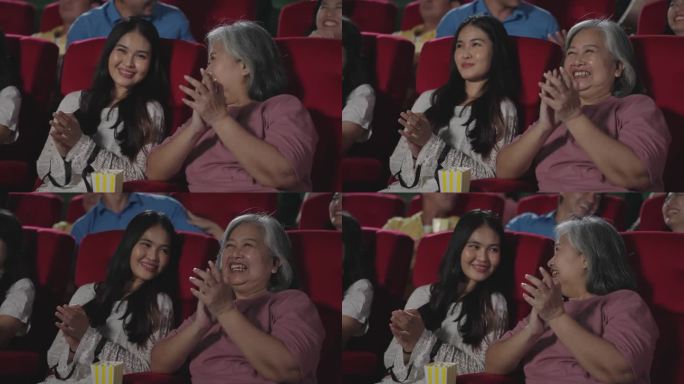 快乐的亚洲母女在影院观看喜剧电影时笑着鼓掌。一群快乐的人坐在电影院的座位上欣赏电影，鼓掌