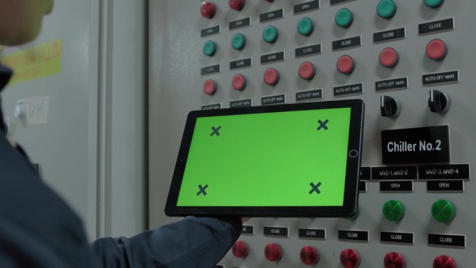 亚洲女电工在控制室拿着绿屏检查的数码平板，记录电气保护继电器参数