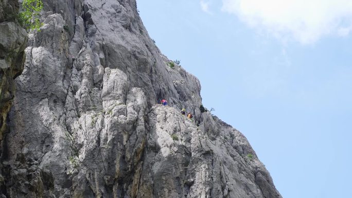 在阳光明媚的日子里，攀岩者站在陡峭的岩石上，徒步到达山顶