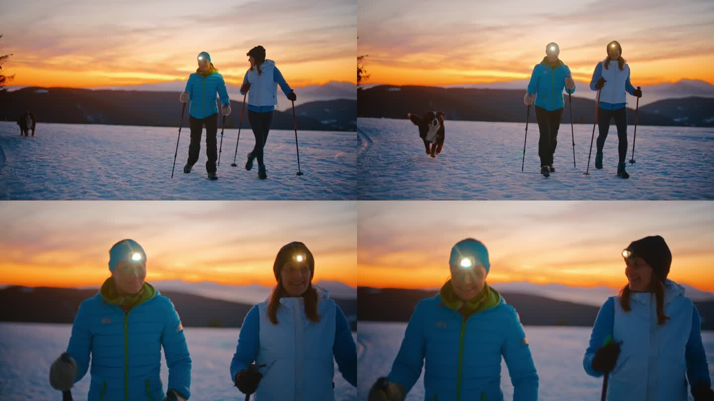 黄昏时分，两名妇女带着她们的狗在雪地里徒步旅行